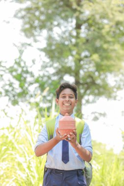 Hintli akıllı çocuk geleneksel domuz kumbarası veya Gullak, Yatırım ve bankacılık kavramını elinde tutuyor.