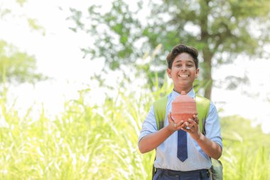 Hintli akıllı çocuk geleneksel domuz kumbarası veya Gullak, Yatırım ve bankacılık kavramını elinde tutuyor.
