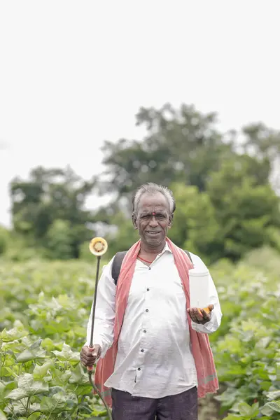 stock image Indian farmer working on farm field, spraying fertilizer on soil and plants. poor farmer , happy farmer , old farm worker