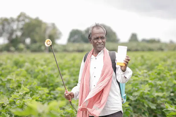 stock image Indian farmer working on farm field, spraying fertilizer on soil and plants. poor farmer , happy farmer , old farm worker