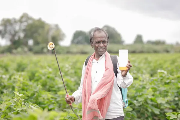 stock image Indian farmer working on farm field, spraying fertilizer on soil and plants. poor farmer , happy farmer , old farm worker