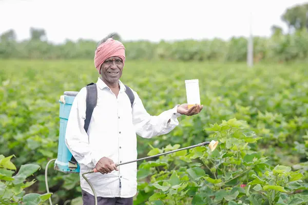 stock image Indian farmer working on farm field, spraying fertilizer on soil and plants. poor farmer , happy farmer , old farm worker