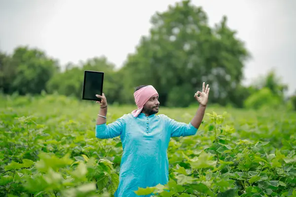 Mutlu genç Hintli çiftçi akıllı telefon kullanıyor, çiftçi tablet gösteriyor, ekranı işaret ediyor