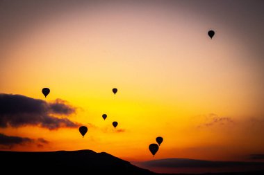 Kapadokya 'da güneş doğarken sıcak hava balonu, ünlü turistik etkinlik.