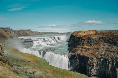 İzlanda 'da turistlerle dolu büyük ve görkemli bir şelale.
