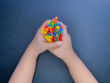 Colourful sticks held in child's hand clipart