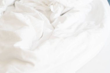 Oteldeki yatağın üzerindeki kırışıklık battaniyesi ve battaniyede güneş ışığı..