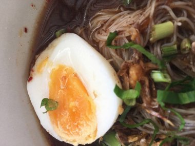 Kaynamış yumurta, tofu, haşlanmış domuz eti ve doğranmış taze soğanla dekore edilmiş ev yapımı yumurta eriştesi..