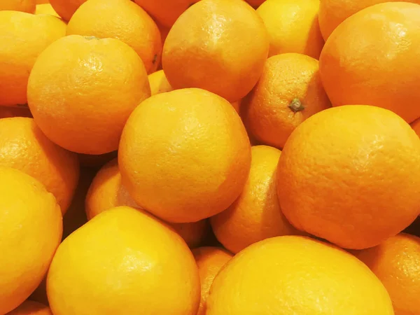 Fresh orange fruit pile on stall in supermarket.