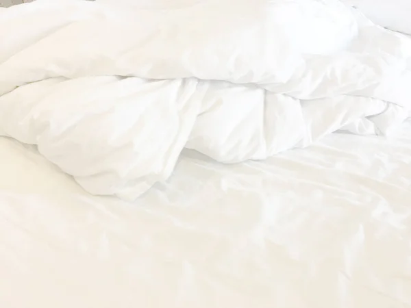 white pillow with messy messy blanket on bed in bedroom Close up of bedding sheets with copy space.