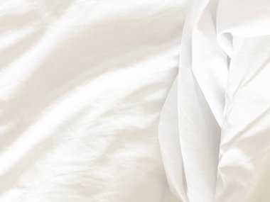 Oteldeki yatağın üzerindeki kırışıklık battaniyesi ve battaniyede güneş ışığı. .