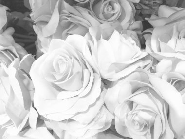 Üzerinde pembe güller, beyaz küçük çiçekler ve güllerin ortasında sahte bir elmas olan siyah beyaz bir makro fotoğraf..