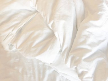 Yatak çarşafları ve battaniye dokusunun üst görünümü soyut arkaplan ve sabahları güneş ışığı.