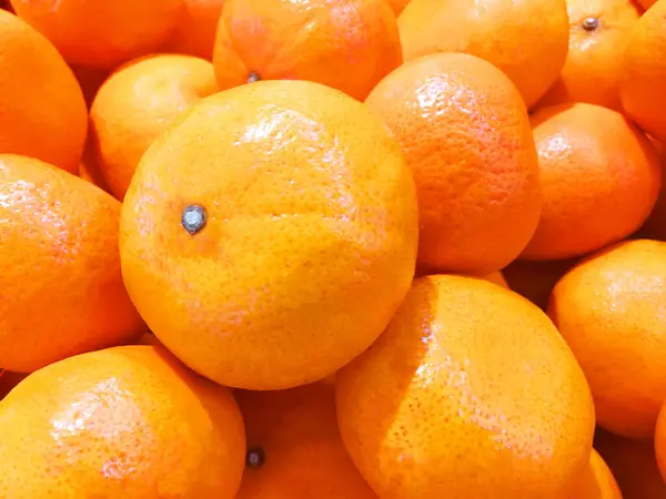 Orange background with closeup on a heap of oranges.