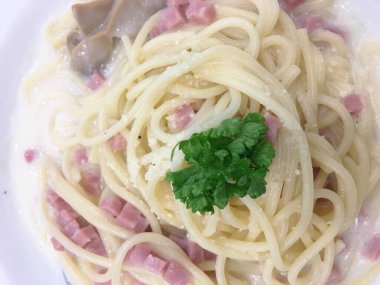 Lezzetli spagetti carbonara, jambon ve krema soslu beyaz tabak..