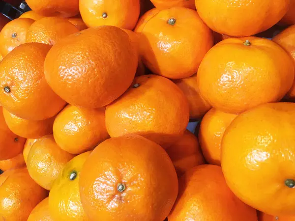Fresh orange fruit pile on stall in supermarket.