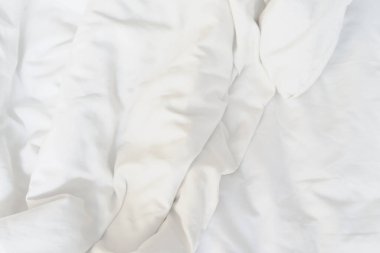 Oteldeki yatağın üzerindeki kırışıklık battaniyesi ve battaniyede güneş ışığı..