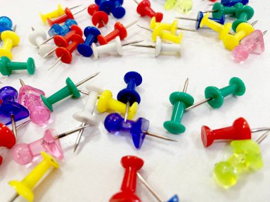 Beyaz kağıt zemin üzerinde renkli plastik raptiyelerin üst görünümü.