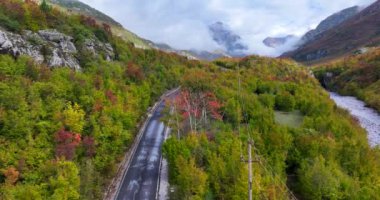 Kuzey Arnavutluk 'taki Thethi ulusal parkının bulutlu dağlarına giden bir dağ yolunun havadan görünüşü. 