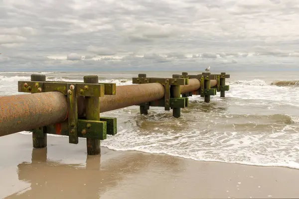 Industrial water pump draining into ocean at beach front