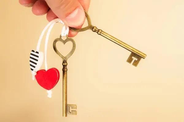 stock image Heart-Shaped Keys and Heart Charms on string being held by fingers