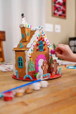 Tahta zencefilli kurabiye evi dekore eden çocuk, renkli tatil sanatları aktivitesi