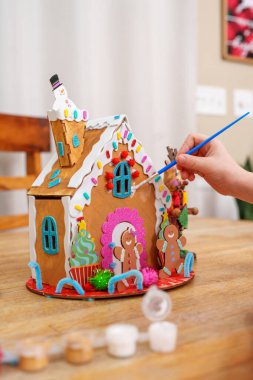 Tahta zencefilli kurabiye evi dekore eden çocuk, renkli tatil sanatları aktivitesi