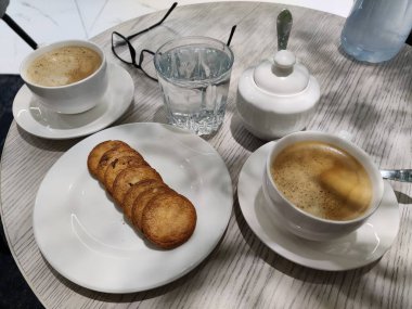 Beyaz arka planı olan bir fincan kahve ve bisküvi.