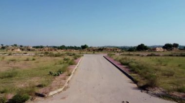 Güneşli bir günde, boş bir T şeklindeki caddenin insansız hava aracı görüntüsü, küçük kayalık bir dağın arka planında geçiyor. Rawalpindi Pakistan 12 Ekim 2024