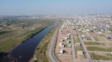 Bir hava manzarası ormanın içinde kıvrılan bir nehri yakalıyor, kıyı yolu kalabalık bir kasabanın yanında akıyor. Rawalpindi Pakistan 12 Ekim 2024