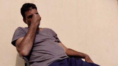 Bir adam tek eliyle gözlerini ovalıyor, aşırı endişe içinde bir şey düşünüyor..