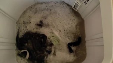 Çamaşır makinesinde kirli çamaşırlar yıkılıyor ve çok fazla köpük görünüyor..