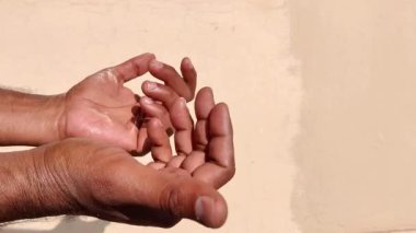 Her iki elin de parlak güneş ışığında bir jest yaparken ki görüntüsü. Parmaklar içe doğru hareket eder, birine yaklaşması için işaret eder. Sıcak gün ışığı, daveti ve aciliyeti sembolize eden anlamlı hareketi artırır..