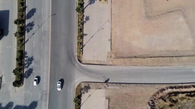 Eğik insansız hava aracı görüntüsü, büyük bulvarda trafik akıyor ve otoparkın yanında boş alan görünüyor..