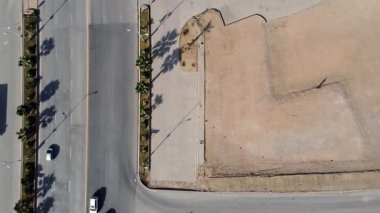 Eğik insansız hava aracı görüntüsü, büyük bulvarda trafik akıyor ve otoparkın yanında boş alan görünüyor..