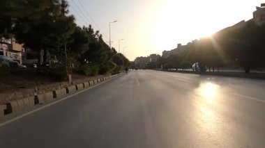 Motosiklet gün batımında yolda altın güneş ışığı ve asfaltta görünen açık şerit işaretleriyle yakalandı.