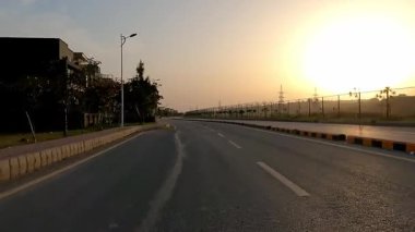 Alacakaranlıkta terk edilmiş yol dramatik dairesel güneş ışığı, bir tarafta evler ve diğer tarafta çitler.