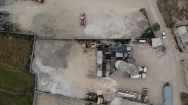 Beton Batarya Fabrikasının endüstriyel insansız hava aracı görüntüsü Otoparklı Karıştırıcı Kamyonlar ve Taşıyıcı Aracıyla Ham Malzeme Stoklarını Bulutlu Gün 4K Hava Görüntülerinde gösteriyor