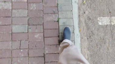 Ayaklar kırmızı ve gri patikada yürüyor, tam kenar boyunca.