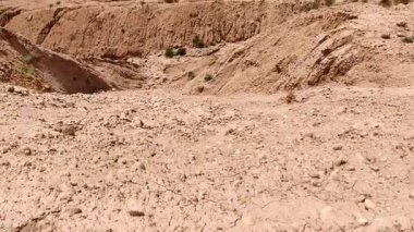 Derin kazı çukurunda çalışan ağır inşaat makineleri. Arka planda yeşil dağlar var. Endüstriyel gelişim, doğa kavramına karşı.