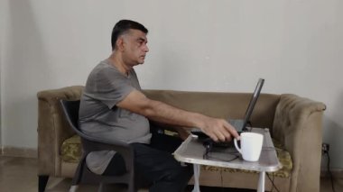 İçişleri Bakanlığı 'ndaki laptopa odaklanmış elinde sıcak çayla masada oturan serbest yazar