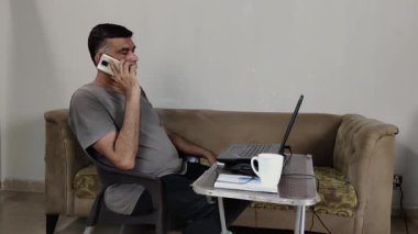 Bilgisayarda Konforlu Ayarlarda yazarken Ev Adamından Çalışma Telefonla Konuşuyor