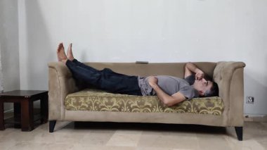 Düşünceli adam, sessiz bir iç çatışma anını işlerken dudaklarını ovalıyor ve tavana bakıyor.