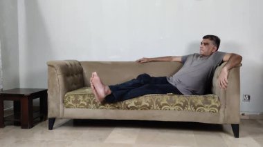 Rahat Duruş içinde oturan adam başını hafifçe hareket ettiriyor. İç huzursuzluk ve zihinsel stres gösteriyor.