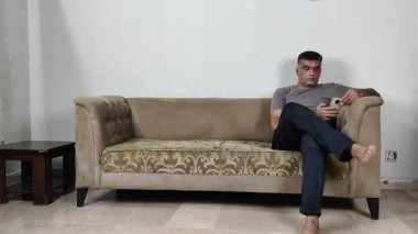 Sakin Adam Tişört Tamir Etti ve Mobil Bakar Koltukta Gevşeme Rutin Teknoloji Nişanı Gösterirken