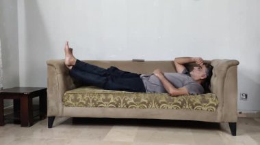 Kanepede sakince uzanan ve yukarı bakan adam duygusal durgunluğu ve zihinsel bağlılığı yansıtır.