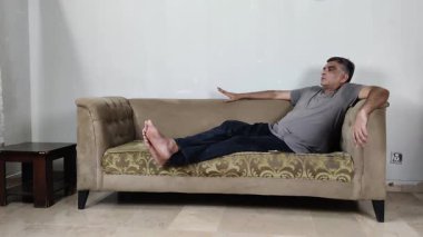 Düşünceli bir ruh halinde otururken Adam Kanepeye Elle vurup Kafasını sallarken Karmaşanın Sessiz İfadesi