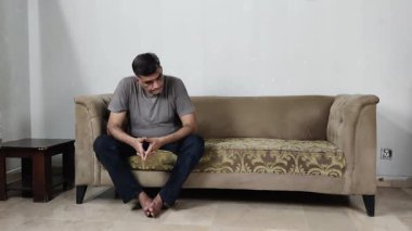 Adam derin bir üzüntü içinde oturur ellerini sıkıca tutar sonra birden sola bakar sanki iç sese tepki verir gibi.