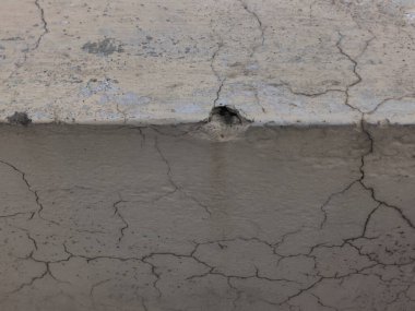 Çatlak ve hasarlı beton bir duvara yakın, küçük bir delik var.
