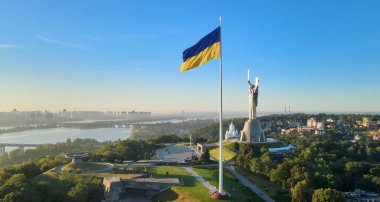 Ukrayna bayrağı Kyiv şehrinin arka planında, Dinyeper nehrinde ve Anavatan anıtında